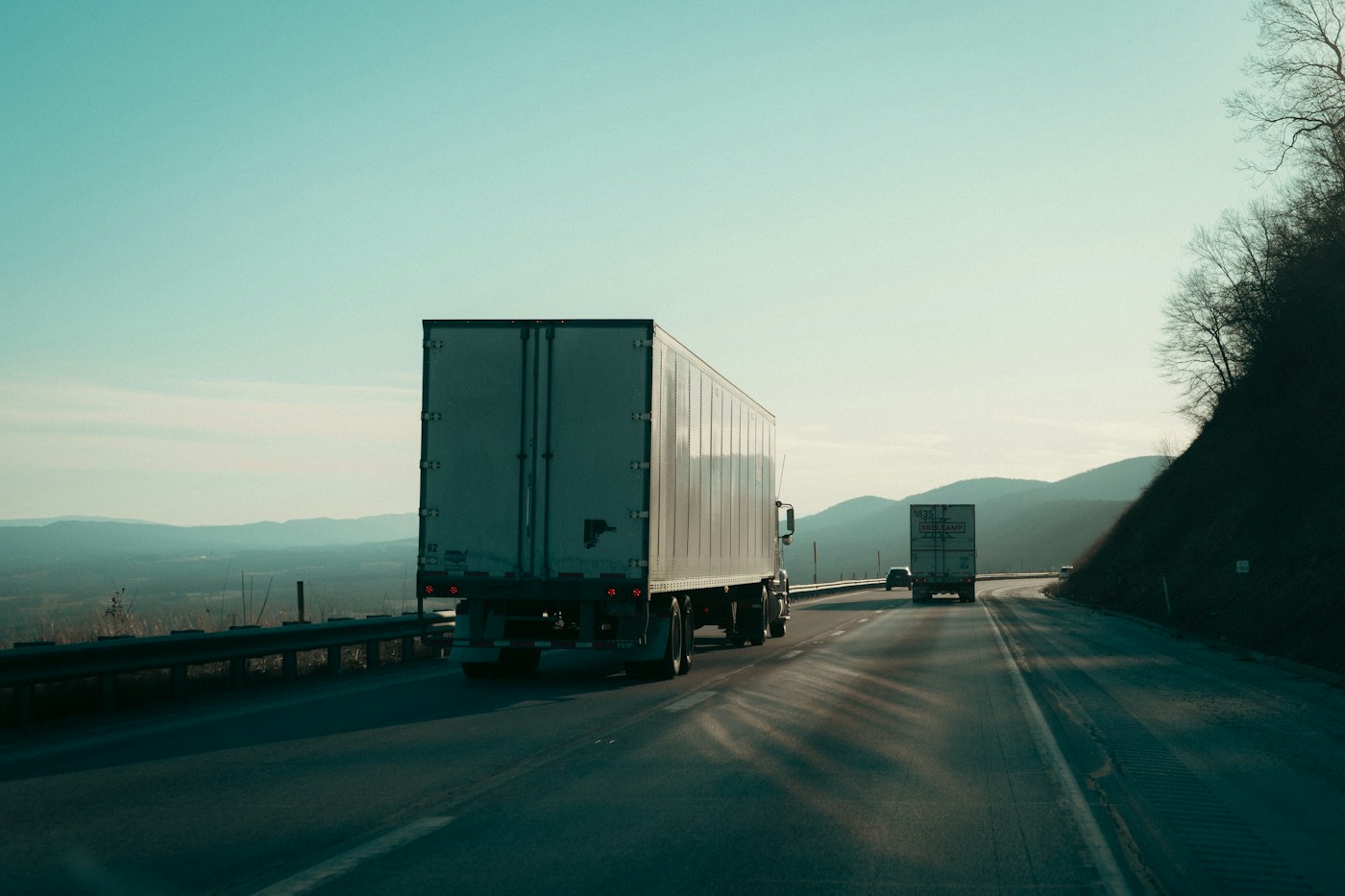 Two semi-trucks traveling on a highway